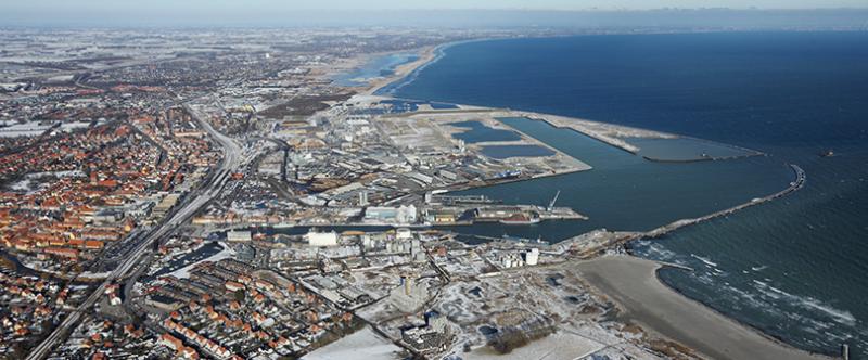 Skråt flyfoto viser mellemstor provinsby med stor havn